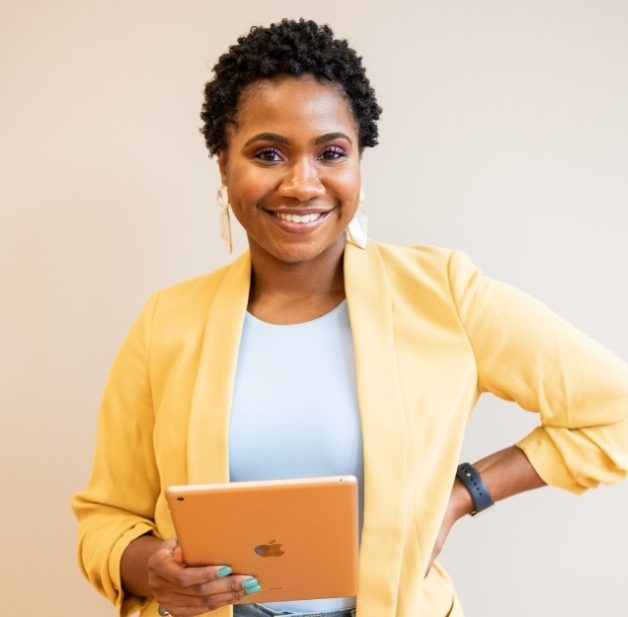 Personne debout tenant une tablette dans une main, portant une veste jaune et un haut bleu clair