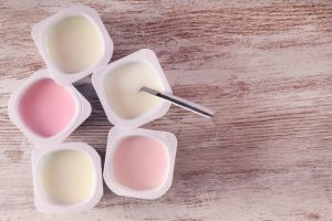 Assortiment de yaourts dans des pots en plastique, sur une table en bois