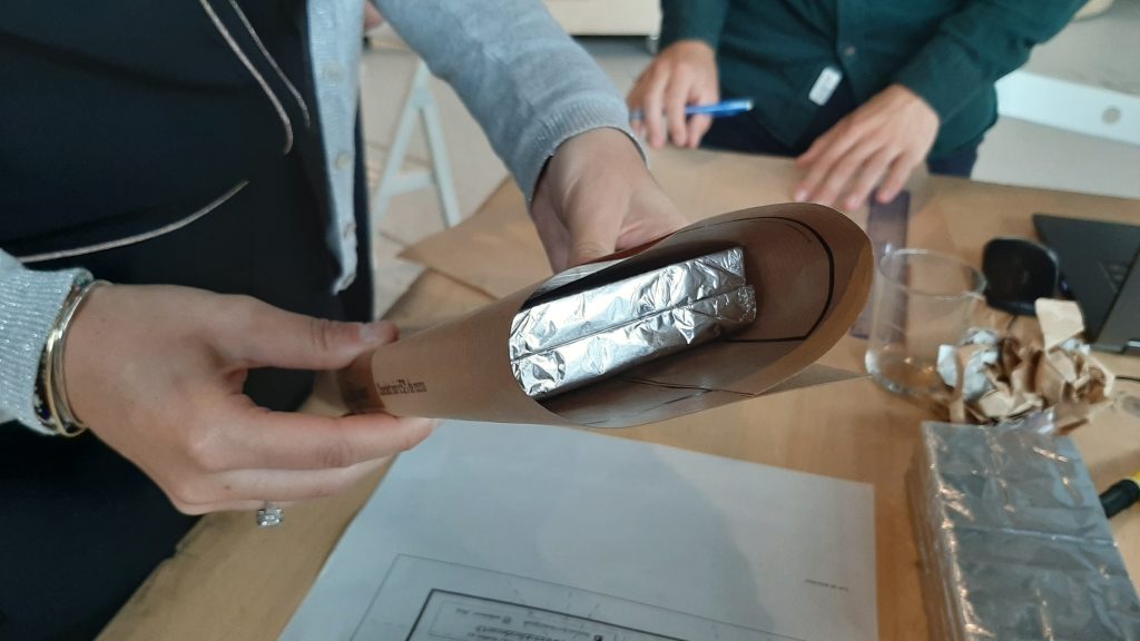 Main tenant un emballage multi-tablettes en papier kraft avec feuilles dâaluminium visibles, illustrant une solution dâemballage sans plastique.